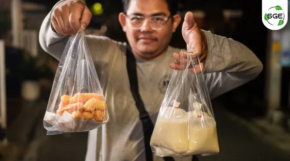 ผู้ชายวัยกลางคน กำลังถือน้ำเต้าหู้ กับปาท่องโก๋ ที่อยู่ในถุงหิ้วพลาสติก